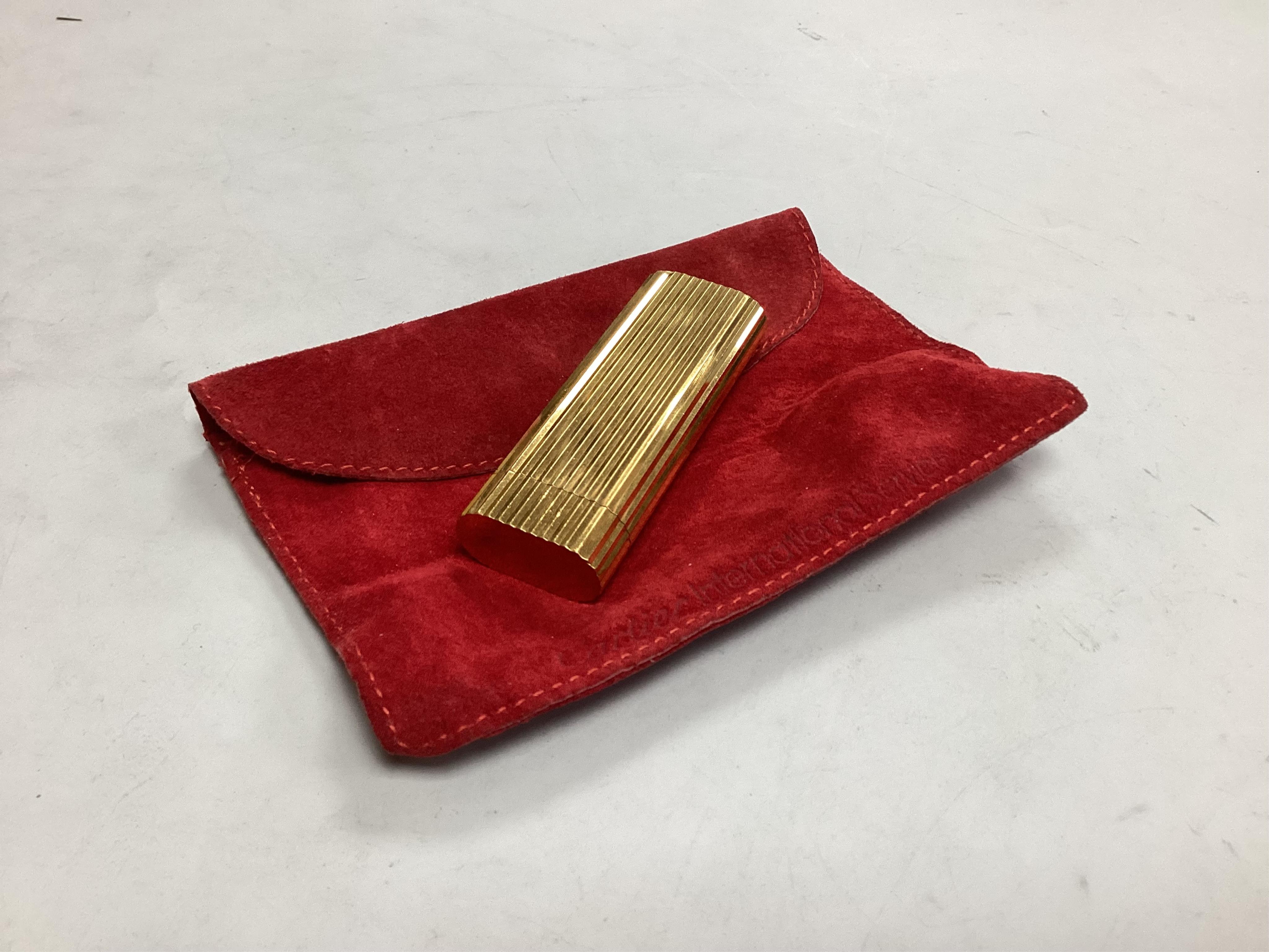 A Cartier lighter, in red suede pouch